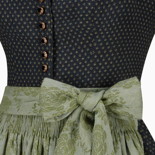 Close-up of a dark blue patterned top with a green floral skirt and ribbon.
