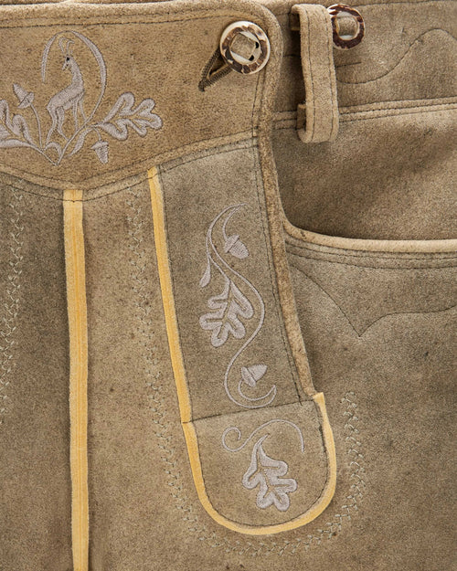 Close-up of brown leather pants with embroidery and button details
