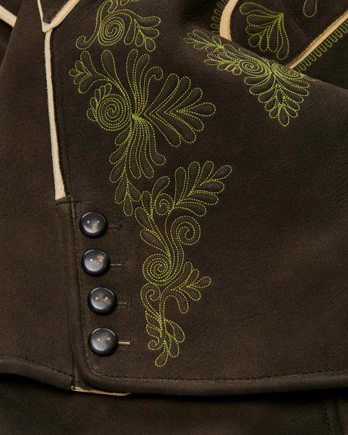 Close-up of a brown garment with green embroidery and buttons.