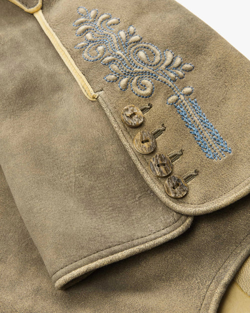 Close-up of a brown leather vest with decorative embroidery and buttons.