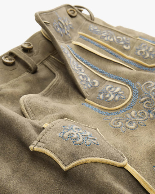 Close-up of a brown garment with blue embroidery on a white background