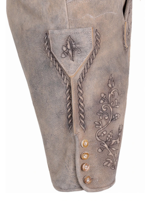 Close-up of a brown leather boot with intricate designs and decorative buttons on a white background