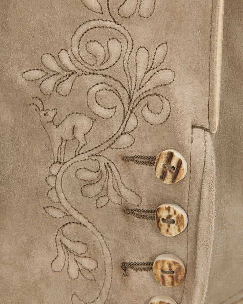 Close-up of a beige fabric with floral embroidery and buttons.