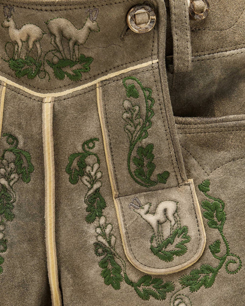 Embroidered fabric with deer and leaf patterns on a brown background