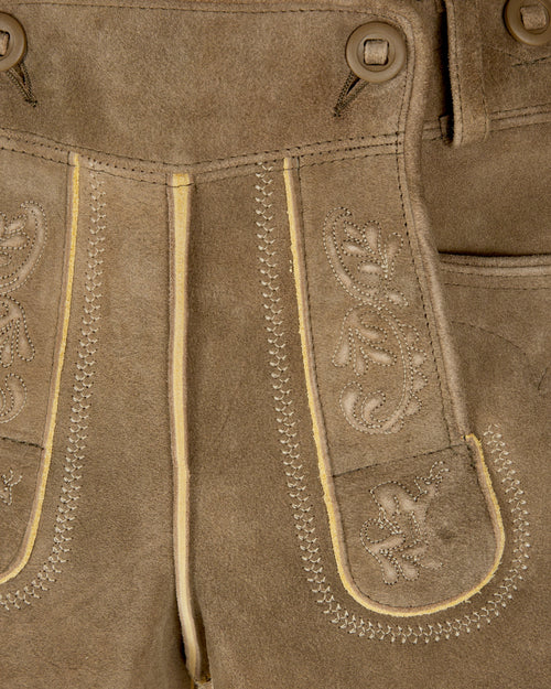 Close-up of brown leather pants with decorative stitching and patterns.