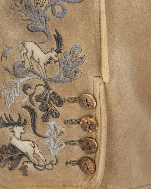 Close-up of a beige fabric with embroidered deer and floral patterns.