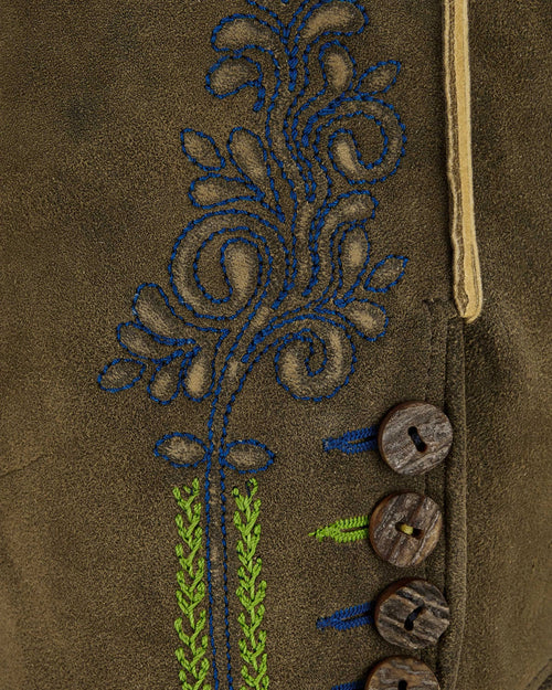 Close-up of a brown fabric with embroidered floral design and wooden buttons.